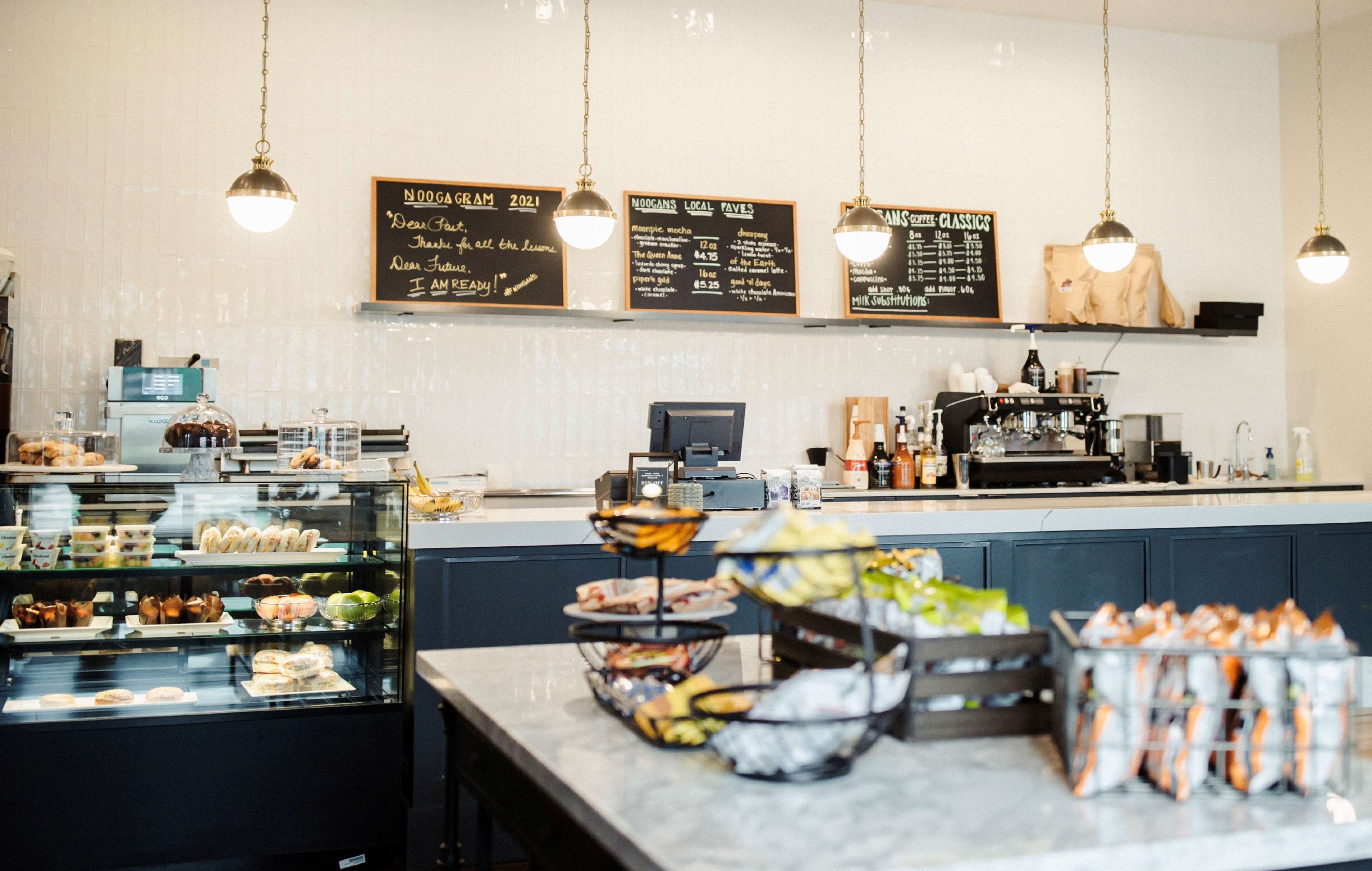 A cafe with a counter, display cases, and hanging lights.