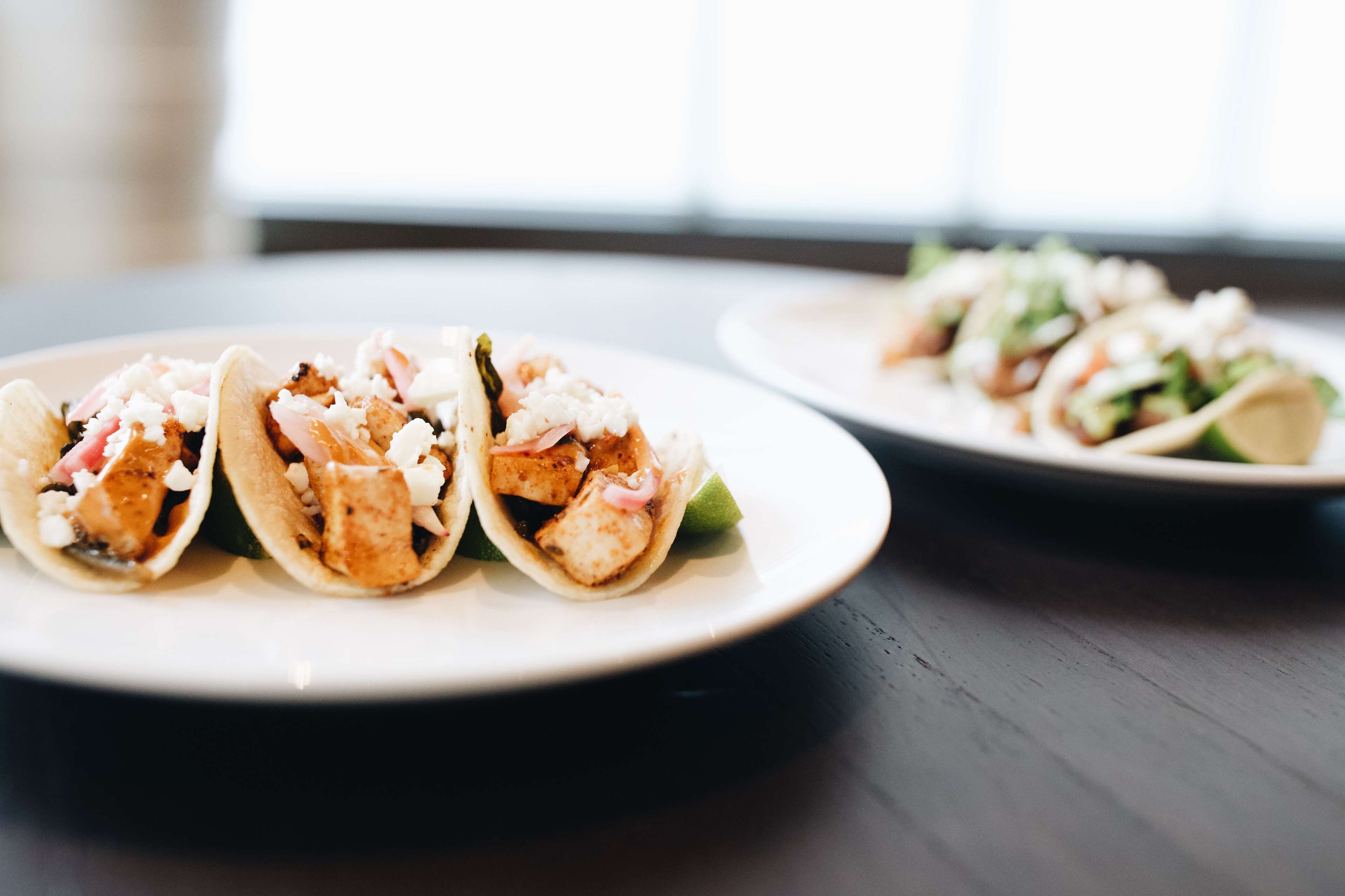 Zwei Teller mit Tacos auf einem Tisch.