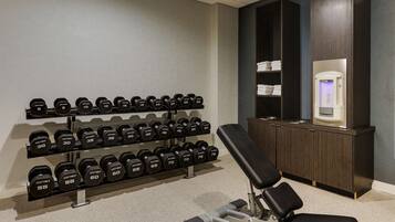 A gym with weight racks, a bench, and a water dispenser.