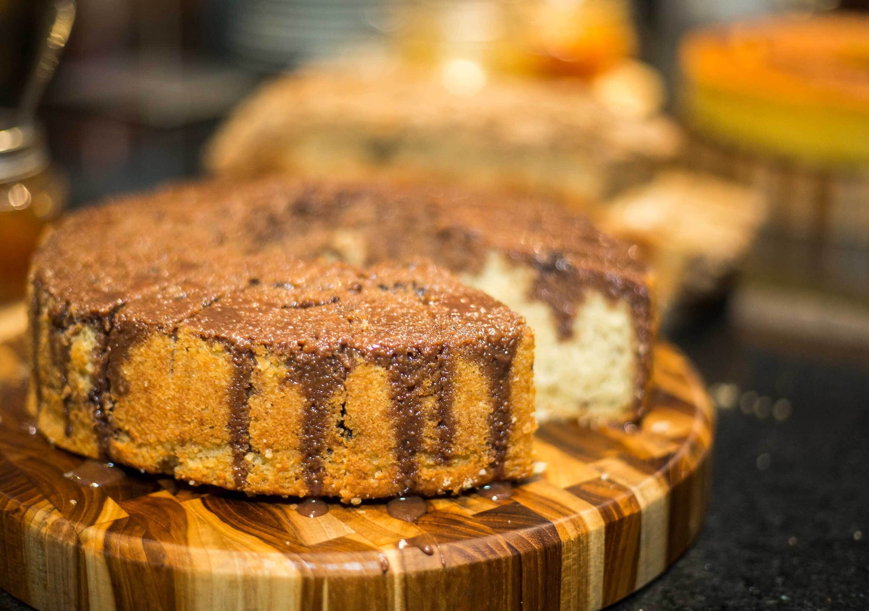 A cake with chocolate drizzle on a wooden board.