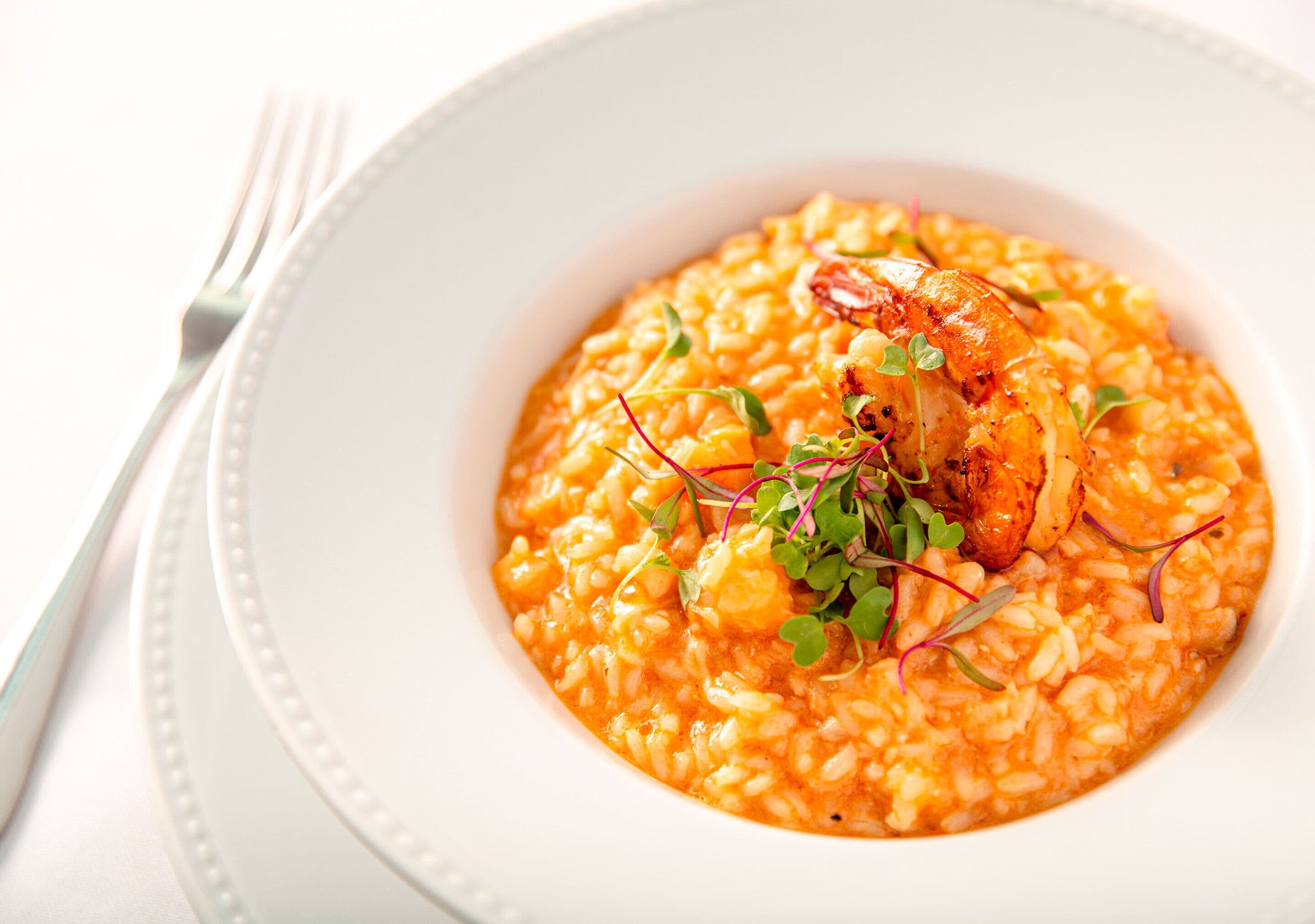 Un plato de risotto con camarones y guarniciones.