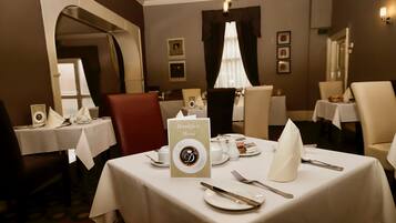 A dining area with tables set for breakfast, including a menu sign, plates, cutlery, and a napkin.