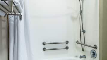 A bathroom with a white bathtub, grab bars, a showerhead, and a towel rack.