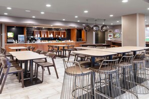 A modern restaurant with multiple tables and chairs, a bar area with a refrigerator and coffee machine, and pendant lighting. - Springhill Suites By Marriott Baton Rouge South (Baton Rouge)