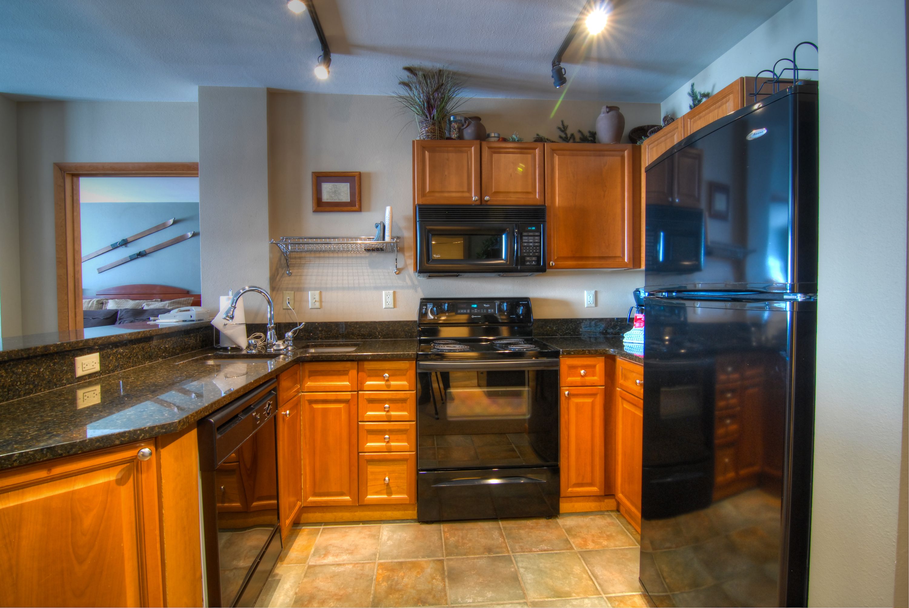 A kitchen with wooden cabinets, a black refrigerator, a microwave, and a stove.