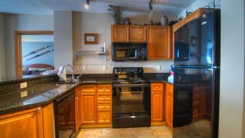 A kitchen with wooden cabinets, a black refrigerator, a microwave, and a stove.