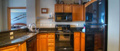 A kitchen with wooden cabinets, a black refrigerator, a microwave, and a stove.