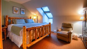 A bedroom with a wooden bed, a chair, a skylight, and two framed pictures on the wall. - Zephyr Mountain Lodge (Winter Park)