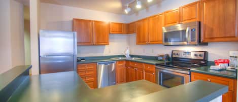 Una cocina moderna con electrodomésticos de acero inoxidable, armarios de madera y encimera de granito.