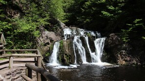 Eine hölzerne Aussichtsplattform mit einem Wasserfall im Hintergrund.