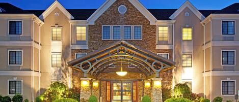 A multi-story hotel with a stone facade, a prominent entrance with a covered porch, and a parking lot in front.