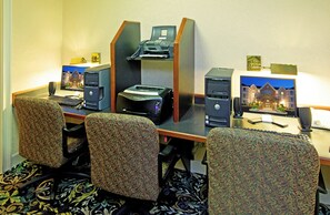 Une chambre d’hôtel équipée d’un bureau, de deux ordinateurs, d’une imprimante et de quatre chaises à motifs.