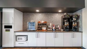 A modern kitchen with white cabinets, a microwave, a trash bin, a coffee station with two coffee makers, and a decorative backsplash. - Extended Stay America Premier Suites Miami Downtown Brickell (Miami)