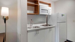 A compact kitchen with a microwave, refrigerator, sink, and wooden shelves. - Extended Stay America Premier Suites Miami Downtown Brickell (Miami)