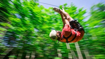 A person in a red shirt and helmet, suspended in mid-air, likely engaging in an outdoor activity.