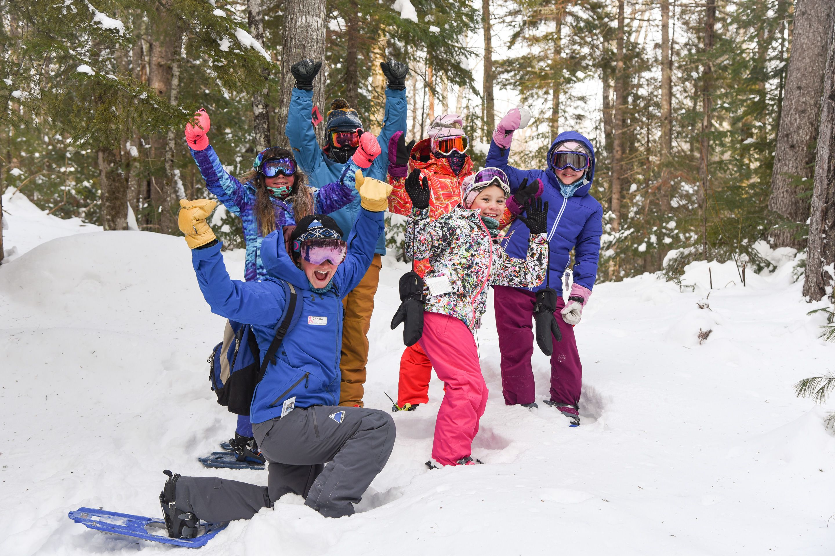 A group of people in winter gear posing in a snowy forest.