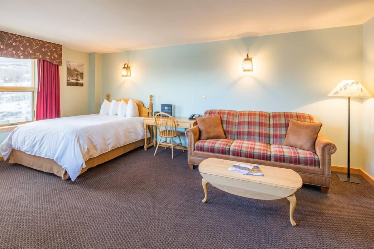 Ein Hotelzimmer mit Bett, Sofa, Schreibtisch und Lampe.