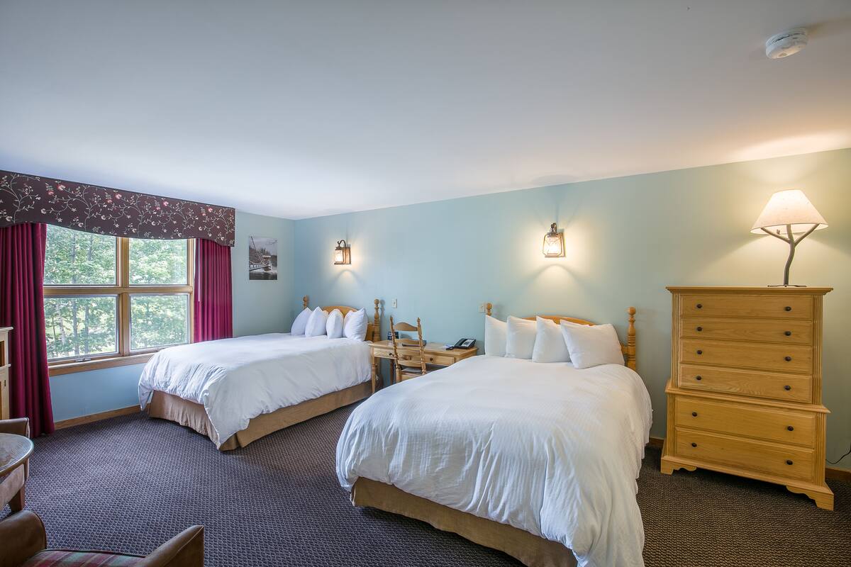 Ein Hotelzimmer mit zwei Betten, einem Schminktisch, einem Schreibtisch und einem Stuhl.