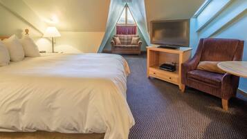 A bedroom with a bed, a TV, a chair, and a small table.