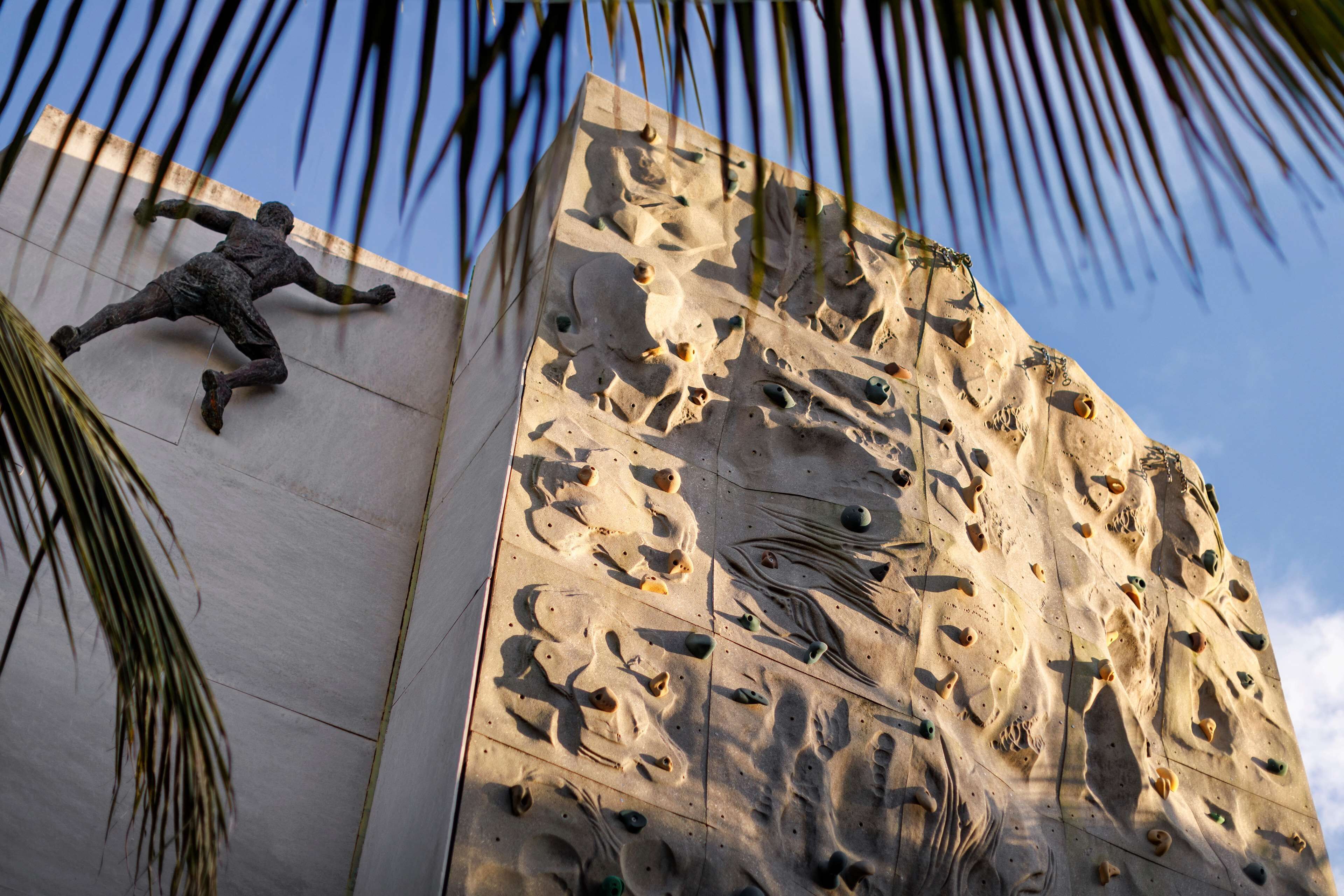 A climbing wall with a statue of a man in motion.