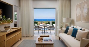 A modern living room with a sofa, coffee table, and a view of the ocean through large glass doors.