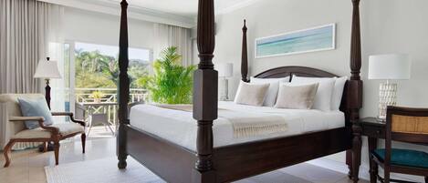 A four-poster bed with a view of the outdoors, a chair, a desk, and a lamp.