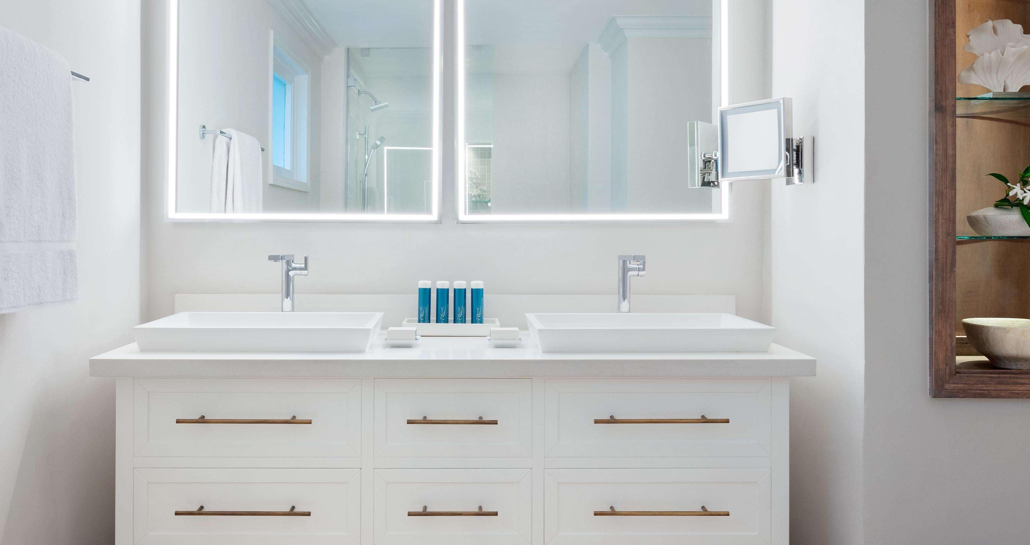 A modern bathroom with two sinks, a large mirror, and a cabinet with drawers.