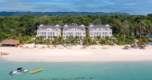 A beachfront hotel with multiple balconies, a sandy beach, and a clear view of the ocean.
