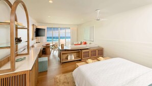 A bedroom with a bed, a desk, a chair, and a TV. There is a window with a view of the ocean. - Beaches Negril Resort - ALL INCLUSIVE (Negril)
