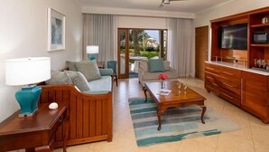 A hotel room with a wooden sofa, a coffee table, a TV, and a dining table.