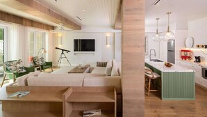 A modern living room with a sofa, a coffee table, and a telescope. There is a kitchen area with a sink, a stove, and a dining table.