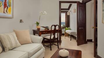 A living room with a sofa, a wooden table, and a chair. There is a door leading to another room.