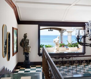 A grand staircase with a checkered floor, a view of the sea, and classical statues.
