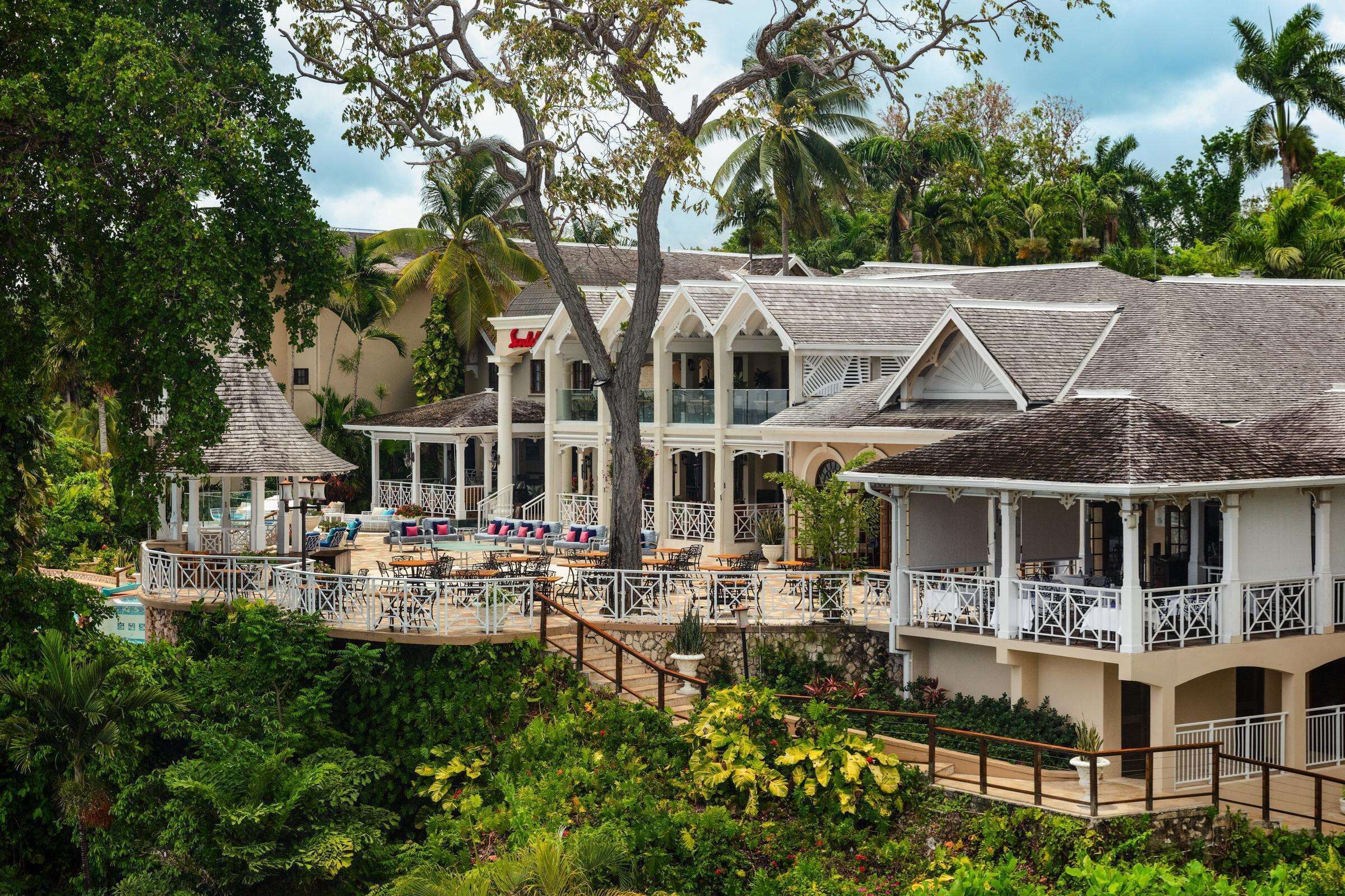 A resort with multiple buildings, outdoor seating areas, and lush greenery.
