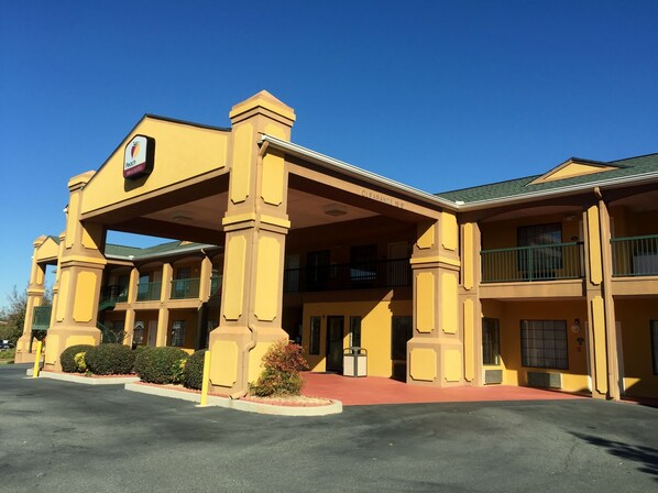 A yellow building with a sign reading "Palo Alto Suites." It has a covered entrance, multiple balconies, and a parking lot in front.