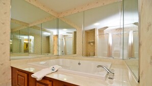 A bathroom with a large mirror, a bathtub, and a vanity with a towel. - Peach State Inn & Suites (Hawkinsville)