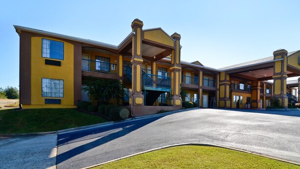 A multi-story hotel with a yellow facade, balconies, and a covered walkway. - Peach State Inn & Suites (Hawkinsville)