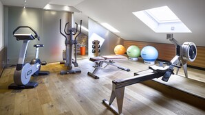 Un gimnasio con equipo de ejercicio, piso de madera y tragaluz.