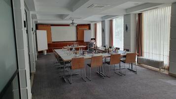 Ein Konferenzraum mit einem langen Tisch, Stühlen, einem Projektor und einer Tafel.