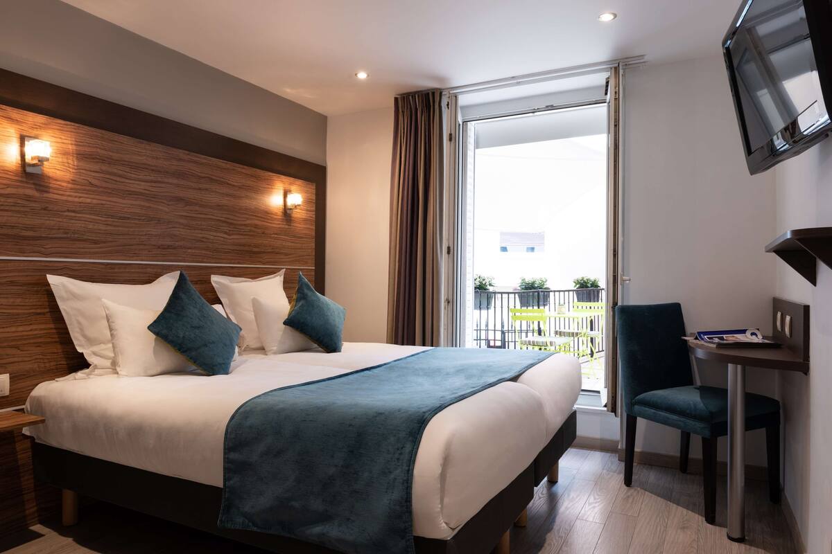 Une chambre d’hôtel avec un grand lit, un bureau, une chaise, une télévision et un balcon avec vue.
