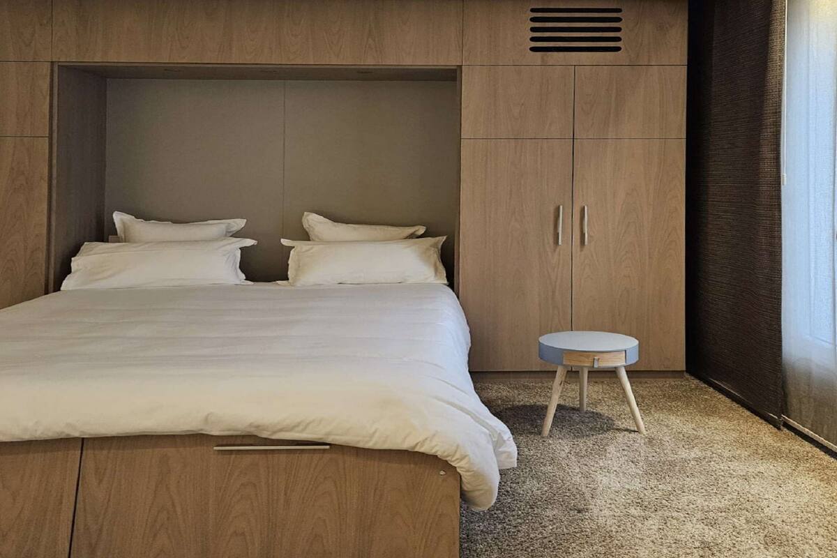 Une chambre avec un grand lit, une armoire en bois et une petite table ronde.