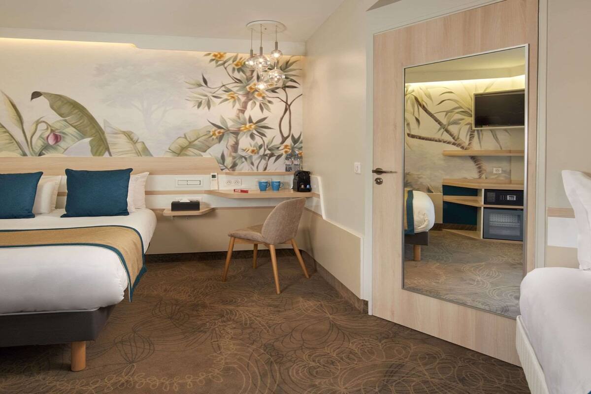 Une chambre d’hôtel avec un lit, un bureau, une chaise et un miroir.