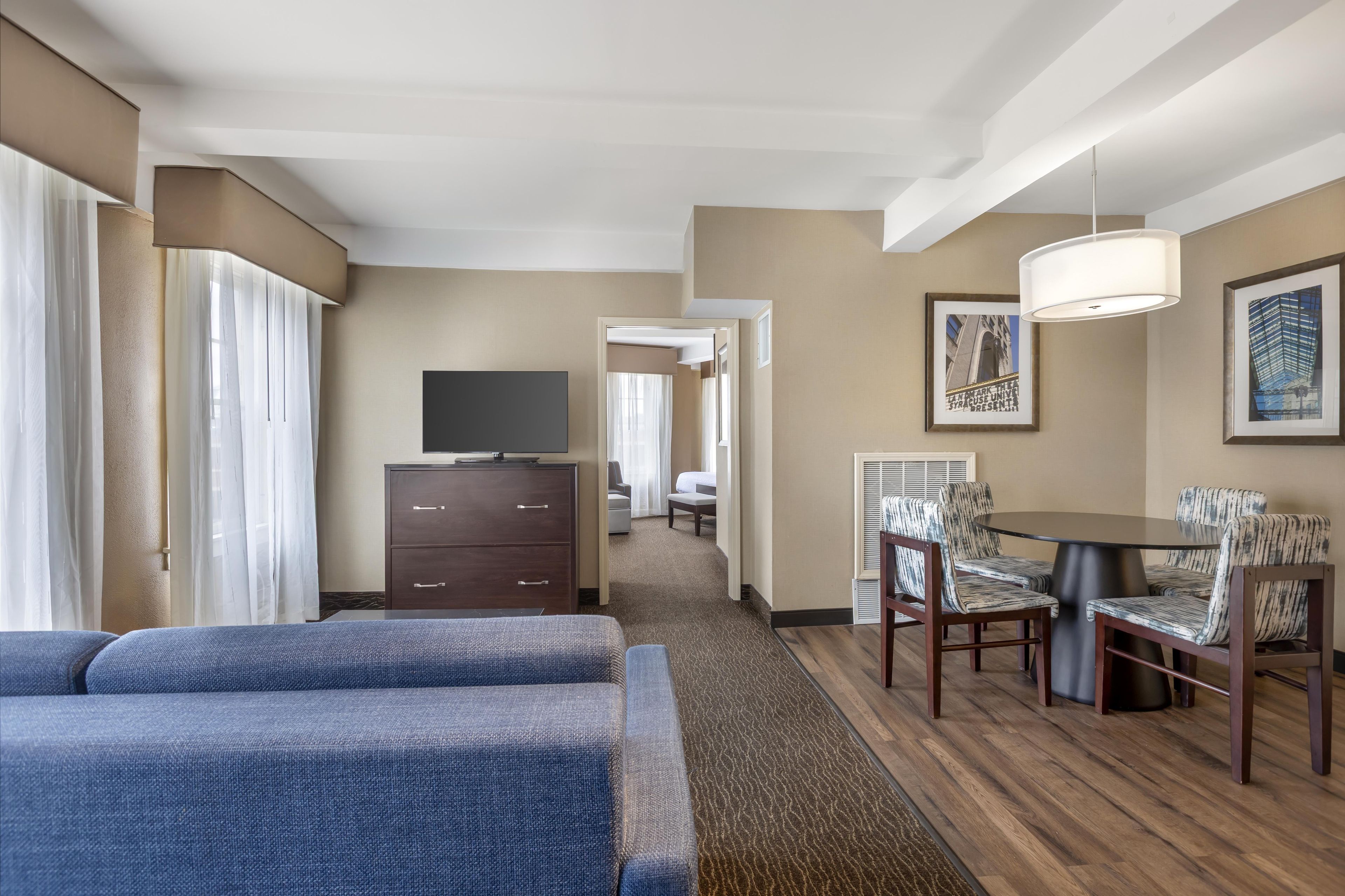 A hotel room with a bed, a desk, a chair, a television, and a framed picture on the wall.