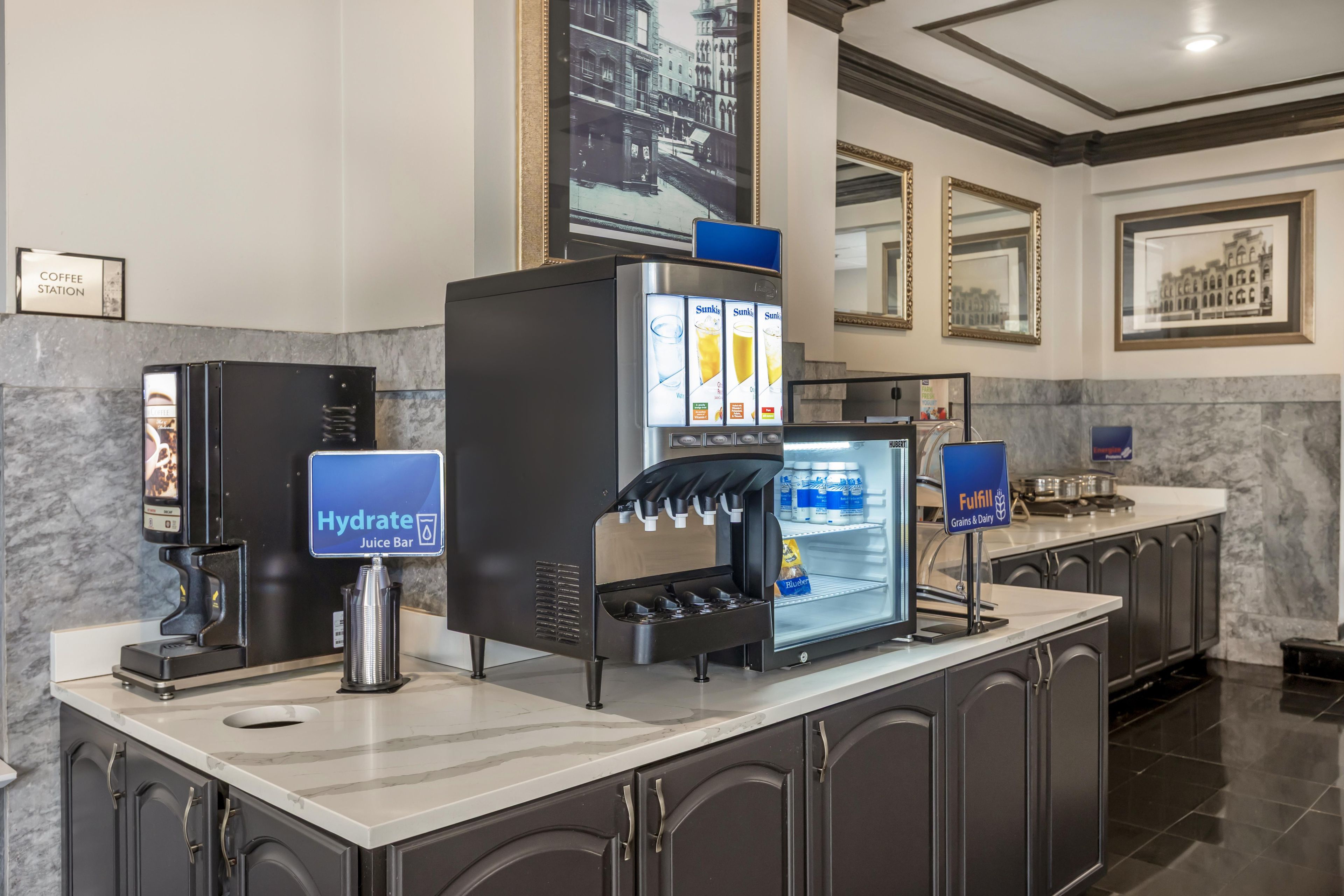 A self-service beverage station with a juice bar, refrigerated display, and a sign for 'Fulfill Grains & Dairy'.