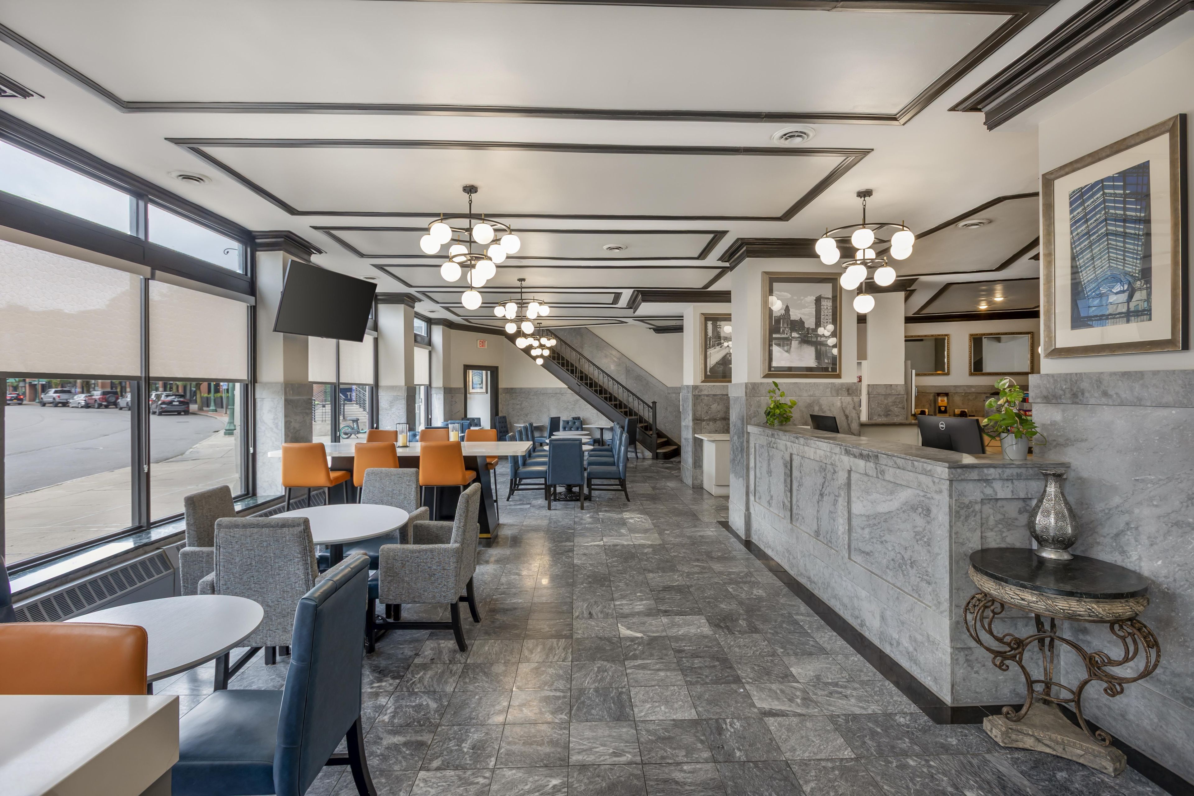 A hotel lobby with a reception desk, seating area, and a staircase leading to upper floors.
