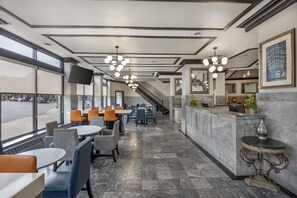 A hotel lobby with a reception desk, seating area, and a staircase leading to upper floors.