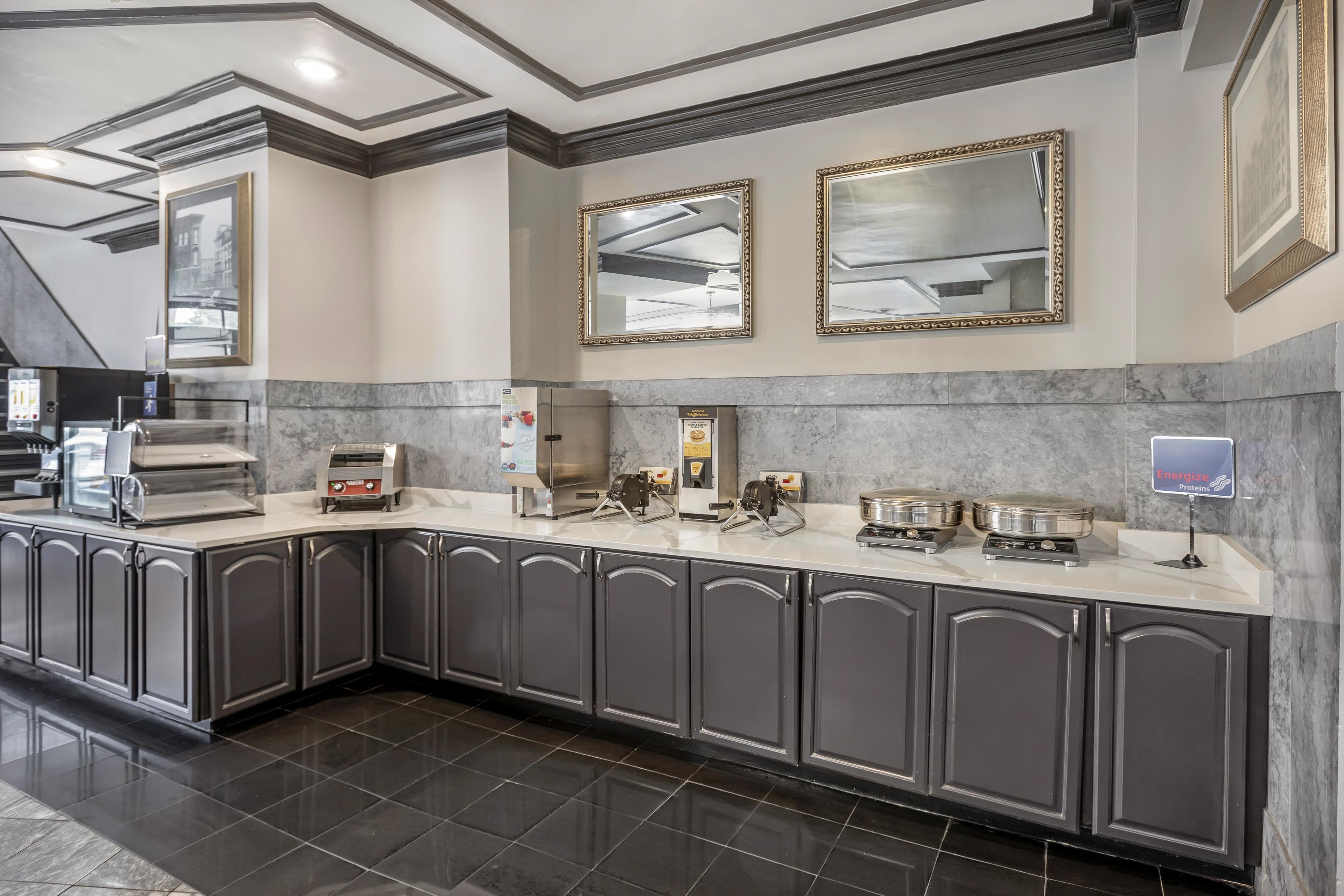 A modern kitchen with marble countertops, stainless steel appliances, and dark cabinetry.