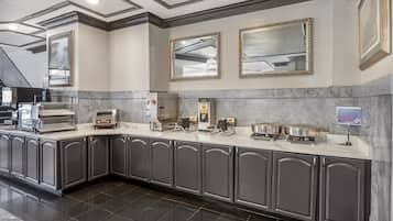 A modern kitchen with marble countertops, stainless steel appliances, and dark cabinetry.