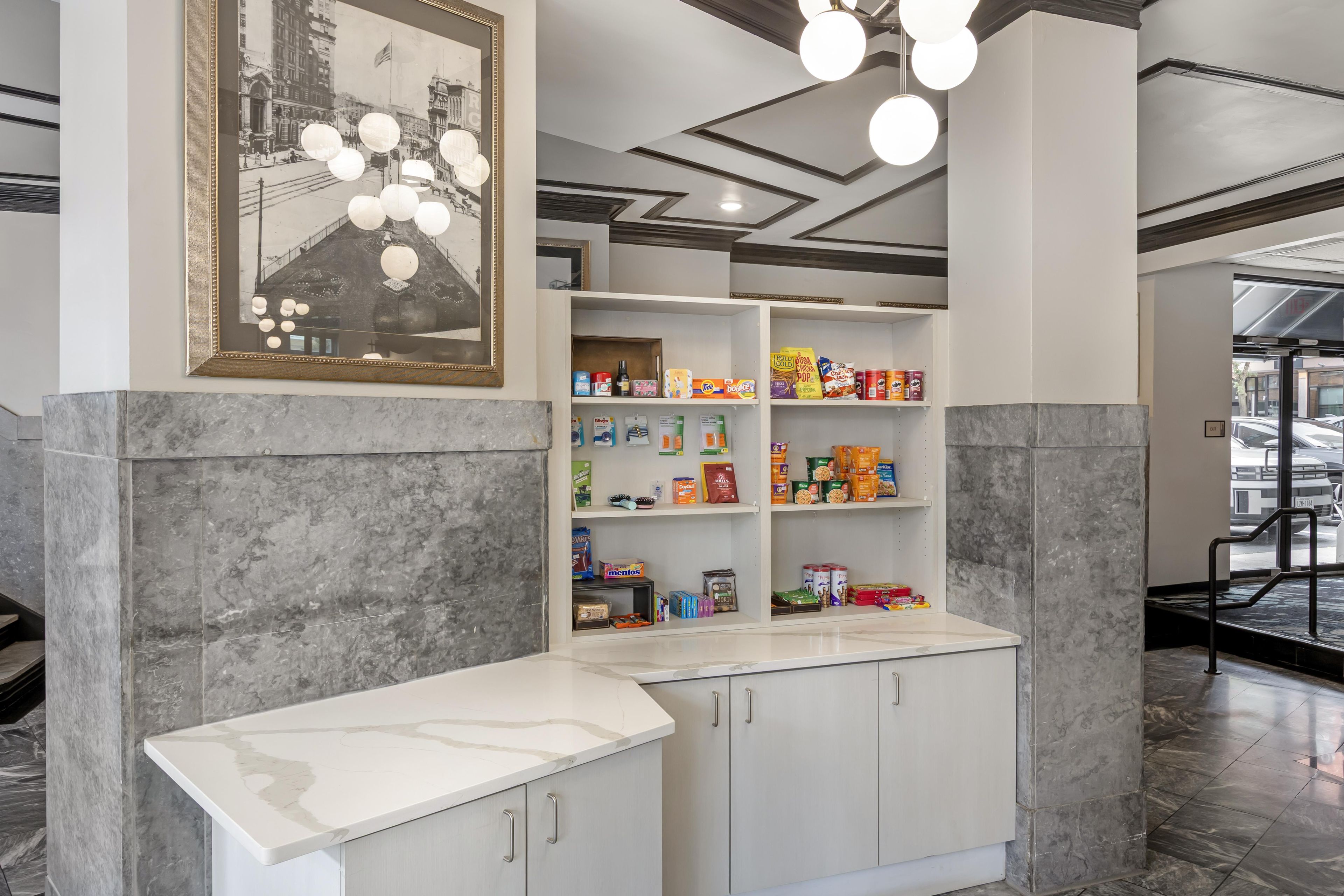 A modern interior with a marble counter, shelves stocked with snacks, and a framed historical photo.
