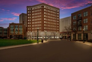 Situated on a wide, curved street, this hotel features a prominent red brick building with a grid of windows.